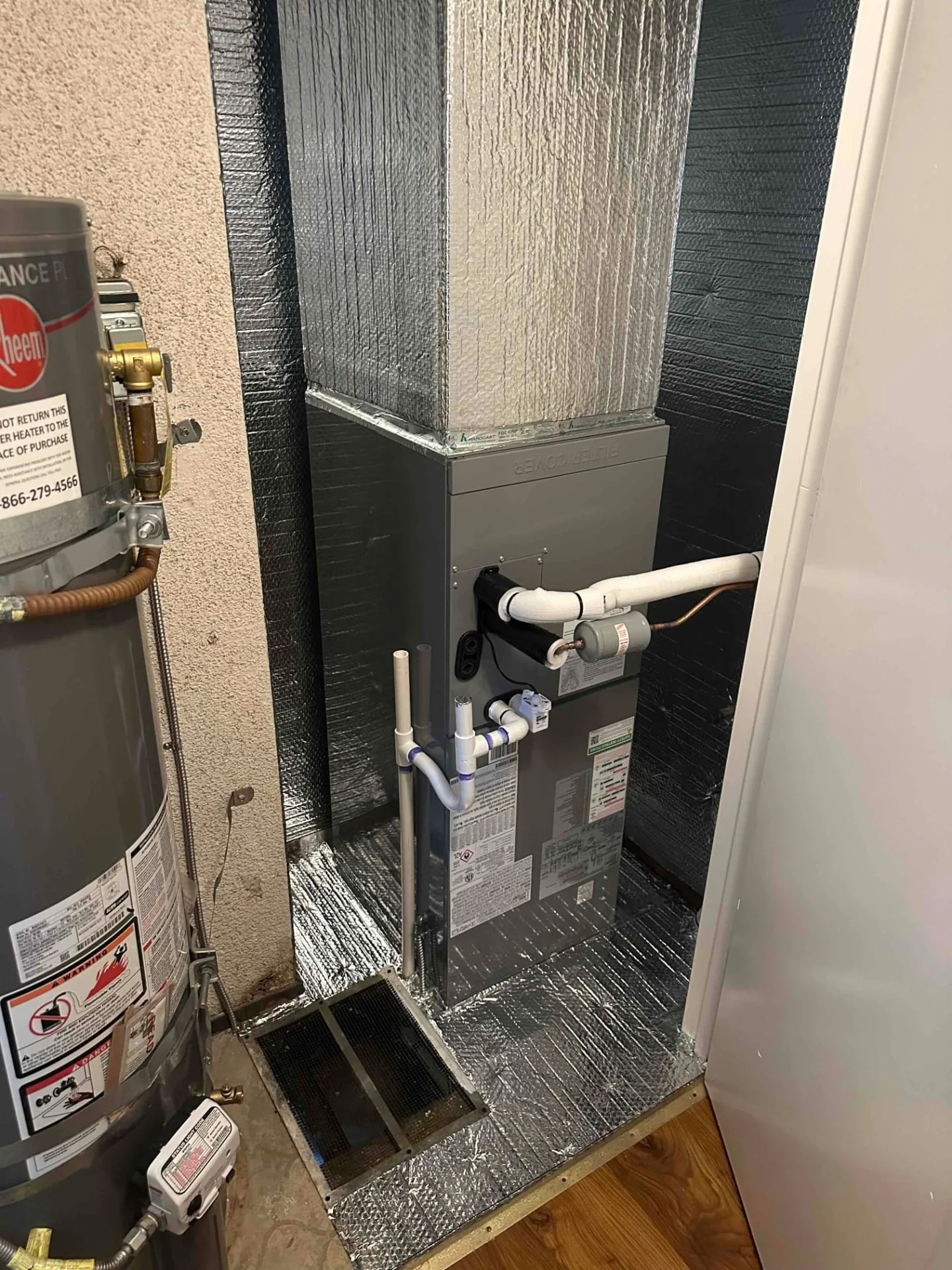Indoor HVAC cabinet and insulated ductwork in a closet with a water heater partially visible