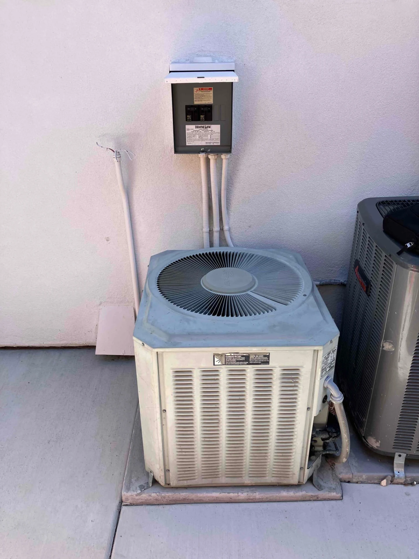 Older outdoor air-conditioning unit beneath an electrical box