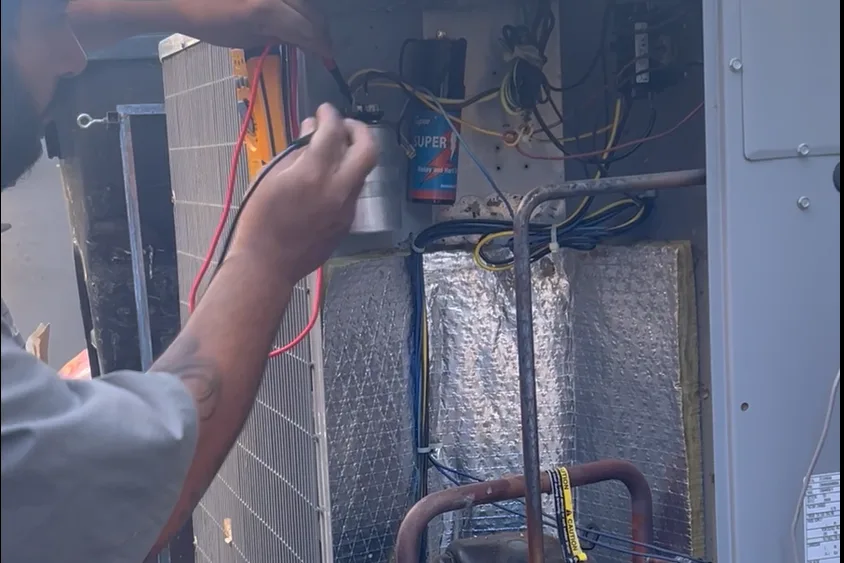 Technician testing electrical components inside an open outdoor air conditioning unit in Almaden, San Jose
