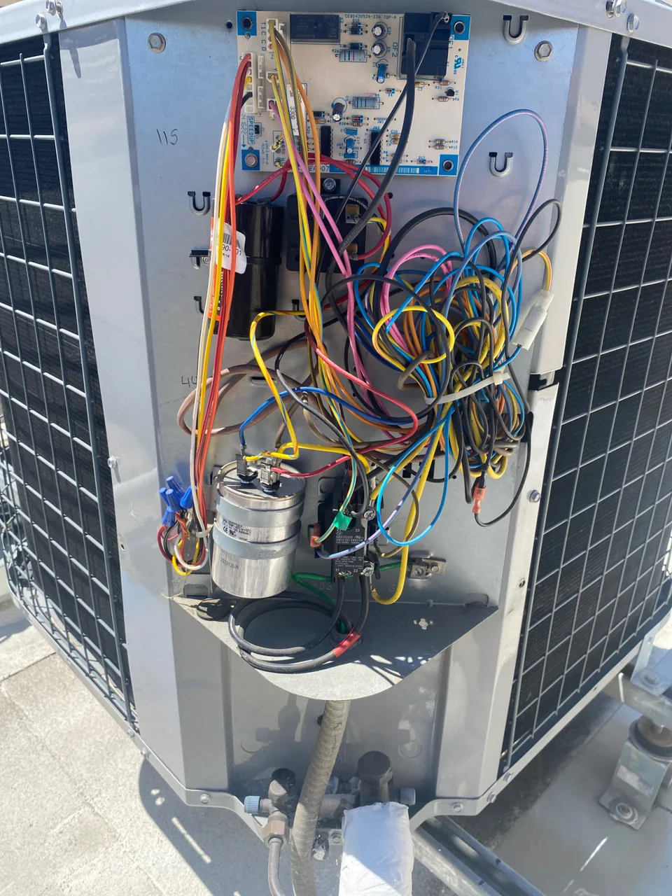 Open outdoor heat pump unit showing its wiring, controls and capacitors