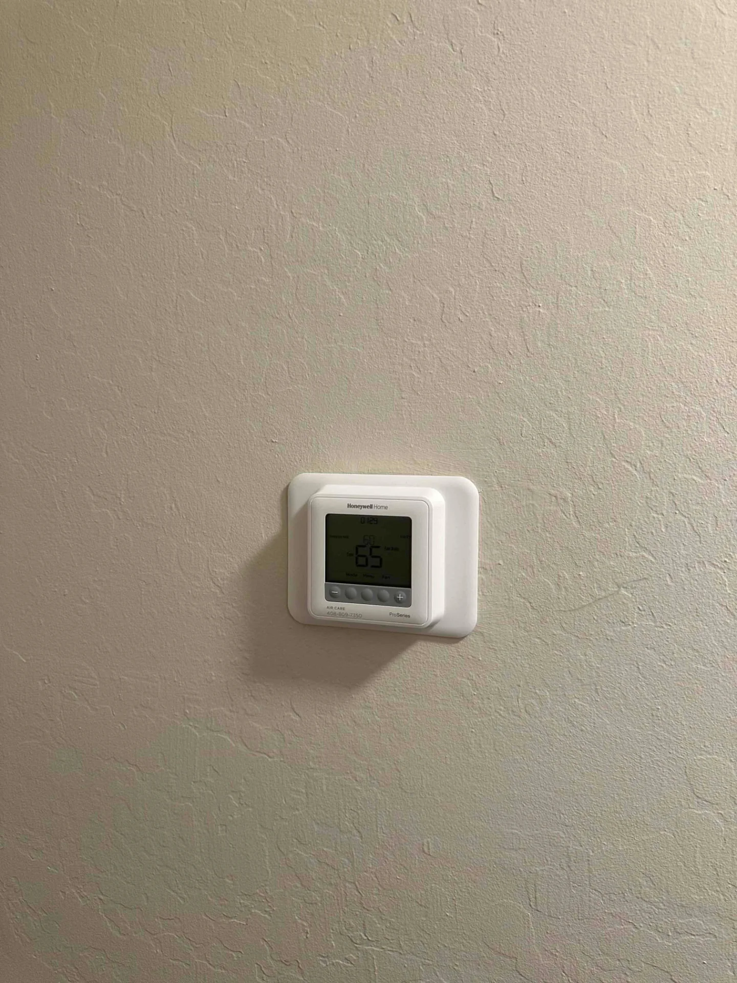 Honeywell thermostat mounted on a textured beige wall