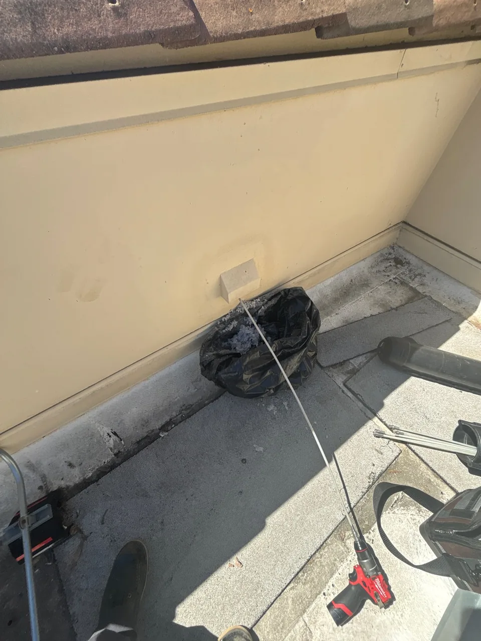 Dryer vent brush and removed buildup beside the exterior vent opening