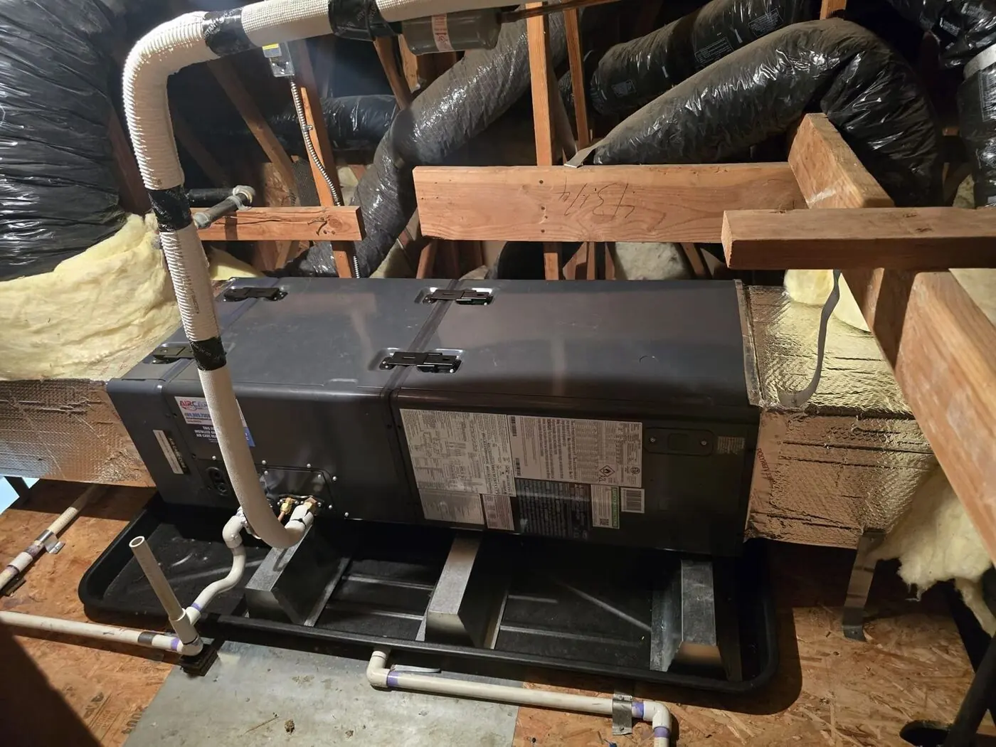 New indoor air handler installed in the attic with condensate drain pan and existing ductwork