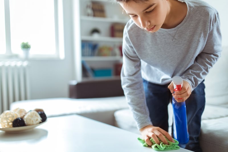 How to Reduce Dust in Your Home. Photo of a child cleaning a table.