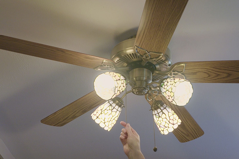 Ceiling Fan being turned on by a hand